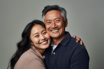 Happy asian father and daughter hugging and smiling at the camera on gray background. Ai generated.