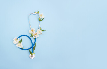 Medicine stethoscope and Alstroemeria flowers on blue background. Medical postcard. Happy doctor's day concept. Selective focus, copy space