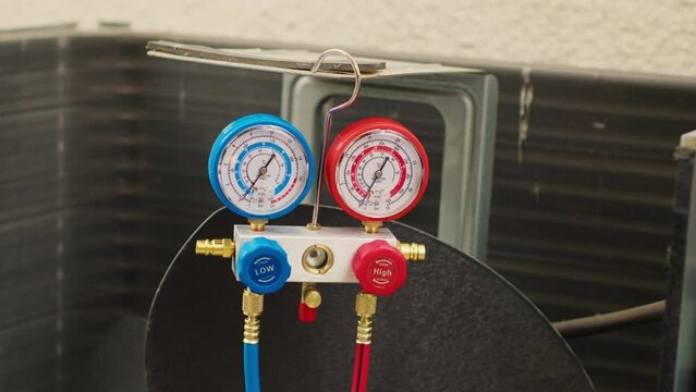 Close up of manifold meters used for checking air conditioner freon in need of service. Set of barometer high or low refrigerant levels benchmarking hvac system internal part