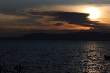 Sunset reflected in the Mediterranean sea of Spain there is a small boat and a beautiful tree and in the background is the beautiful sunset
