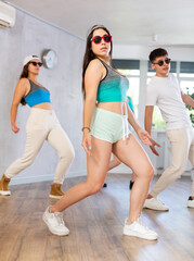 Obraz premium Group of happy young sports people exercising dancing in modern gym studio