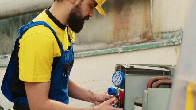 Licensed expert using pressure measurement device for checking air conditioner freon in need of maintenance. Skilled technician working with manometers to look at refrigerant levels