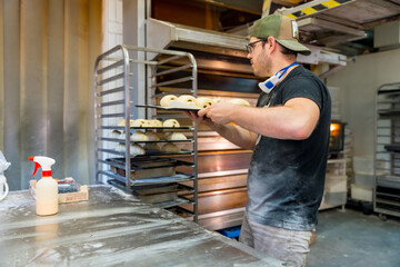 Baker of bakery in the workshop workshop of artisan bakery preparing croissant and neapolitan on the trays