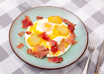 Appetizing dish of scrambled eggs and ham slices with potatoes