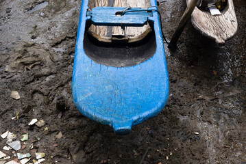 Blue and light colored fishing canoe resting on the sands of the river.