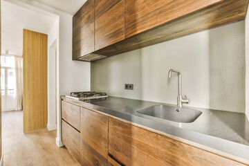 a modern kitchen with wood cabinets and stainless steel sink fauced on the countertop in an open space