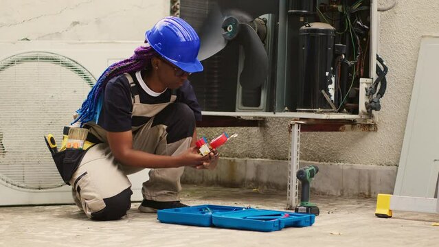 Knowleadgeable engineer unpacking toolkit with professional manometer equipment needed to check freon levels. Certified technician preparing for annual HVAC system maintenance