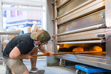 Baker of bakery in the workshop workshop of artisan bakery baking loaves in the oven