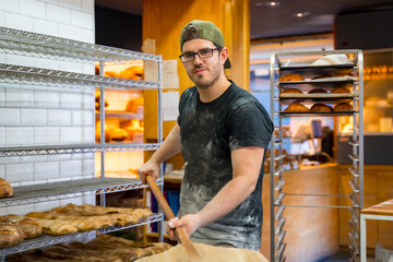 Portrait of baker of bakery in the workshop workshop of artisan bakery with the shovel of bread for the oven