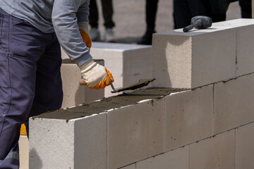 The bricklayer is working. Building a wall of aerated concrete. Gasbeton wall - obrazy, fototapety, plakaty