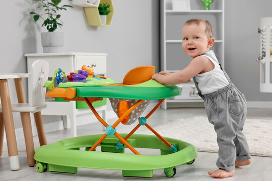 Cute baby making first steps with toy walker at home