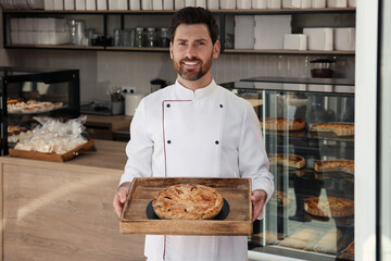 Professional baker with freshly baked pastry in store