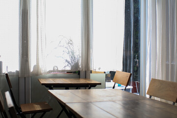 Wooden table, modern chairs and white curtain. Interior design of stylish dining room restaurant on background. 