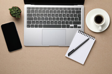 Modern laptop, notebook and cup of coffee on beige table, flat lay. Space for text