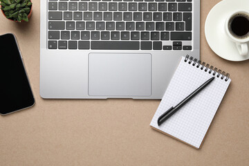 Modern laptop, notebook and cup of coffee on beige table, flat lay. Space for text