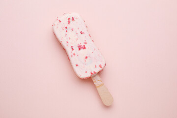 Delicious glazed ice cream bar on pale pink background, top view