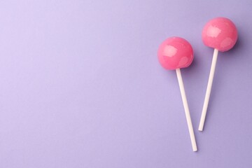 Tasty lollipops on violet background, flat lay. Space for text