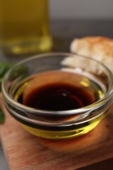 Bowl of organic balsamic vinegar with oil on wooden board, closeup