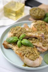 Delicious fried chicken drumsticks with pesto sauce and basil on table