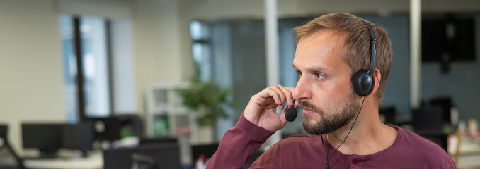 Caucasian bearded man with a headset. Male call center worker. Widescreen. 