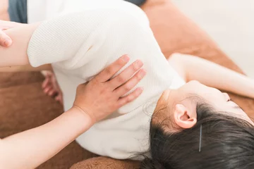 Foto auf Acrylglas Massagesalon 肩のマッサージをするマッサージ師・カイロプラクター・セラピスト・整体師・理学療法士のアジア人女性 