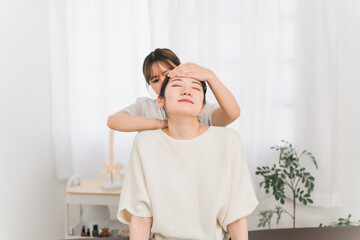 首・頭のマッサージをする整体師の女性と患者（ストレートネック・首こり・鞭打ち）
