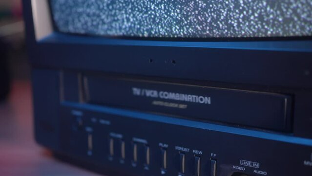 Pushing a VHS Video Cassette Tape Inside the VCR of an Old TV
