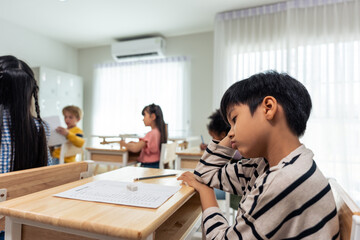 Asian young boy student doing an exam test at elementary school. 