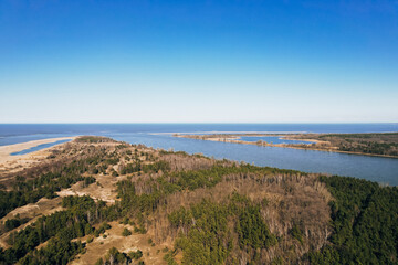 Aerial view drone of river goes into the sea. Delta of Vistula river goes in Baltic Sea in Sobieszewo Gdansk Poland. Forest and small village around river