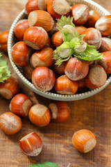 Hazelnuts with green leaves .Nut Harvest Season. nuts in a cup on a wooden table. Healthy fats. Fresh harvest of hazelnuts. Farmed organic ripe hazelnuts.