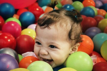 Fototapeta na wymiar Bebé riendo en una piscina de pelotas