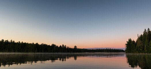 Fototapeta na wymiar a lake in northern Canada at dust with a gradient sky from blue to pink 