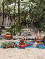 Tropical sandy garden with green plants and palm trees with indigenous ritual objects in Tulum