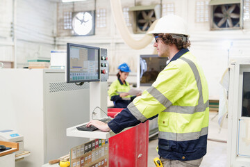 Caucasian carpenter man stand with pressing buttons on CNC machine control board in carpentry workshop factory. Production line of the wooden working industrial factory.