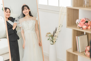 Fototapeta premium 鏡を見ながら結婚式のウェディングドレス・ベールの衣装合わせ・試着をする花嫁 