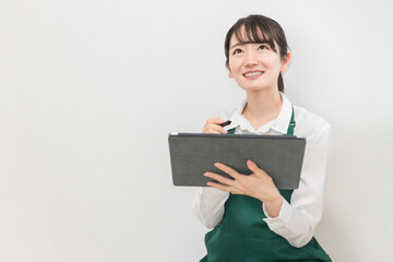 Obraz premium コンビニ・スーパーでタブレット端末を使って在庫管理・棚卸しをする店員・バイトの女性 