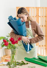 Portrait shot of Asian professional successful female florist designer shop owner entrepreneur businesswoman in apron standing holding flower bouquets posing look at camera in floral garden store.