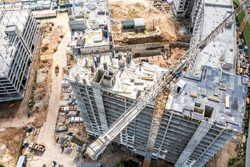 crane working near multistory apartment building under construction. aerial photo, top view.