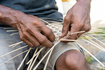 hands of an Indonesian man working with bamboo