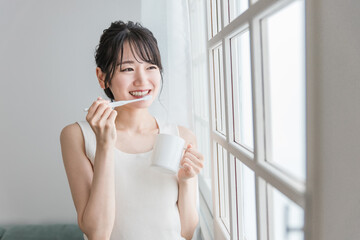 朝、歯磨き・歯をブラッシングする笑顔のアジア人女性
