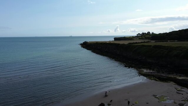 Aerial view Traeth Lligwy Jurassic rocky weathered rugged Anglesey coastal shoreline, reverse orbit across bay
