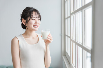 家で朝ミルク・牛乳を飲むアジア人女性
