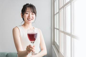 家で赤い飲み物を昼飲みするアジア人女性（赤ワイン・アセロラ・ザクロ・シソ・ポリフェノール・タンニン）
