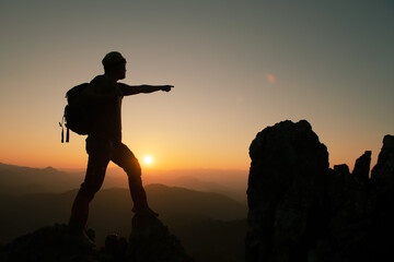 Young man with a backpack enjoying the sunset on the top of the mountain Travel traveler on valley scenery mockup background Mountain climbers watch the sunlight shining on their country journey.