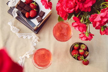 Aesthetics summer table settings. Couple of glasess with red homemade, strawberry infusion. Strawberry and chocolate. Roses bouquet. Flat lay