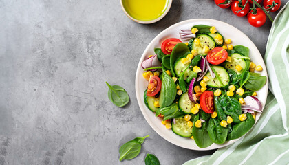 Spring vegan salad with spinach, cherry tomatoes, corn salad, baby spinach, cucumber and red onion. Healthy food concept. Gray stone table. Top view. Copy space - obrazy, fototapety, plakaty