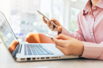 A woman sitting in a café is using her credit card to make online purchases.