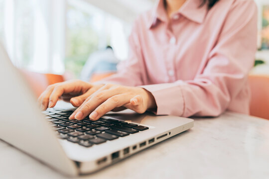 A freelancer is sitting in a caf&eacute;, using a laptop to reply to clients' inquiries and requests.