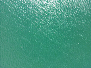 Naklejka na ściany i meble Aerial view of a crystal clear sea water texture. View from above Natural blue background. Turquoise water reflection. Turquoise ocean wave. Summer sea. Drone. Top view
