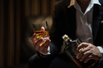 Businessman sitting Holding a Glass of Whiskey Drink Whiskey in the liquor store room